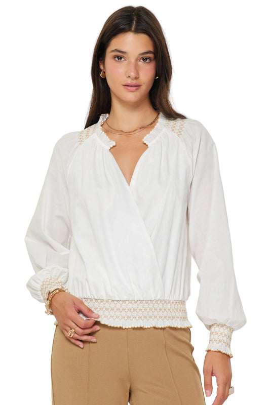 Woman wearing a white blouse with lace details on a plain background