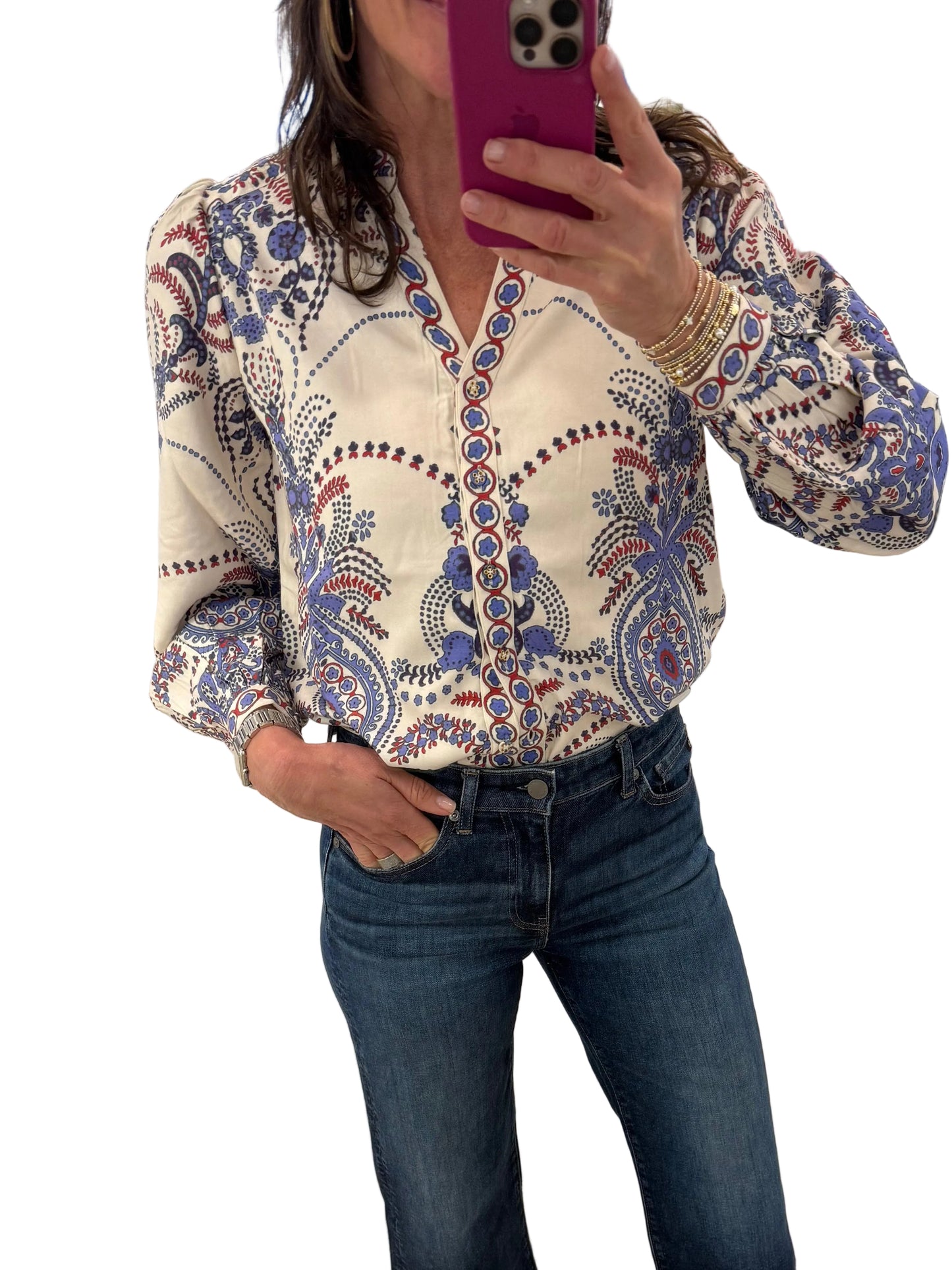 Person wearing a patterned shirt and jeans standing in a store with a mirror reflecting their image.