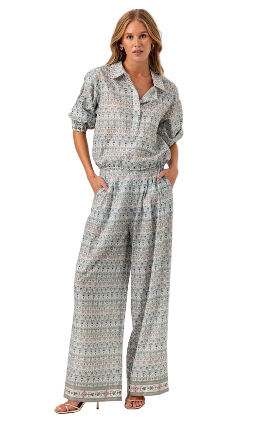 Woman wearing a patterned shirt and wide-leg pants on a white background