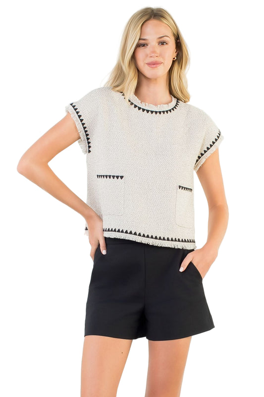 Model wearing cream fringe tweed sleeveless top with crew neckline”