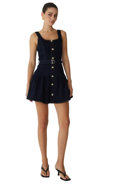 Woman wearing a navy dress with gold buttons on a white background