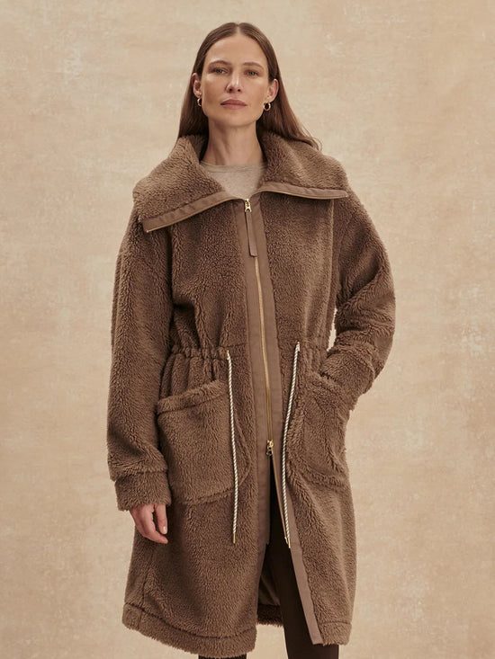 Woman wearing a brown coat against a beige background