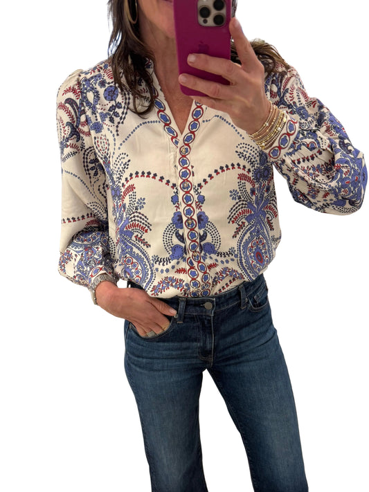 Person wearing a patterned shirt and jeans standing in a store with a mirror reflecting their image.