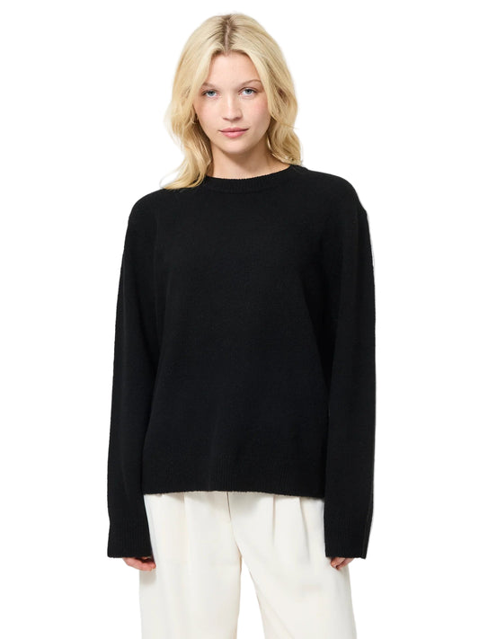 Person wearing a black sweater and white pants on a white background