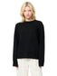 Person wearing a black sweater and white pants on a white background