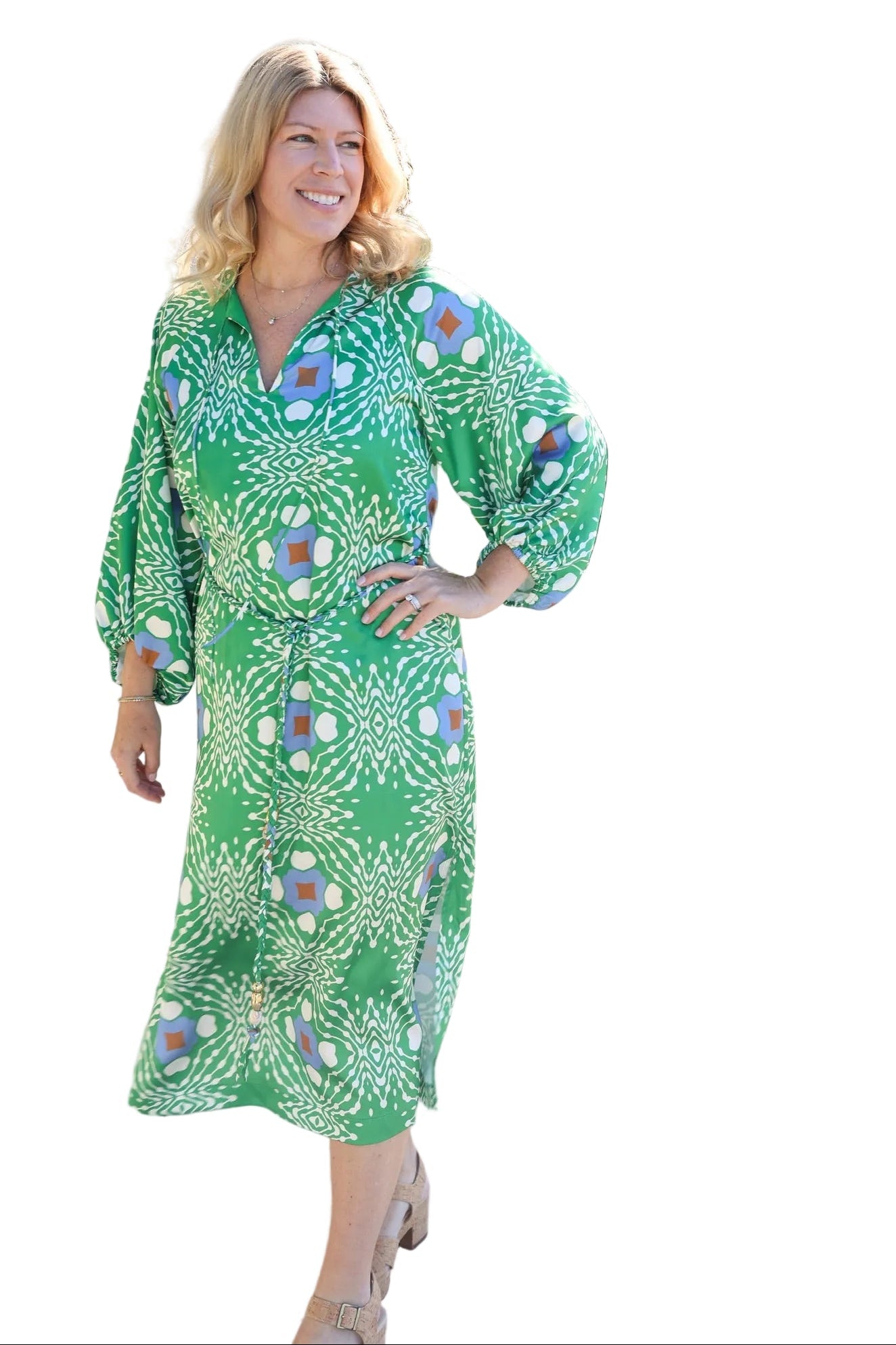 Woman in a green patterned dress standing in front of a palm tree