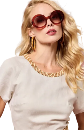 Woman wearing red sunglasses and a gold necklace against a red background
