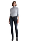 Woman wearing a gray turtleneck and dark jeans on a white background