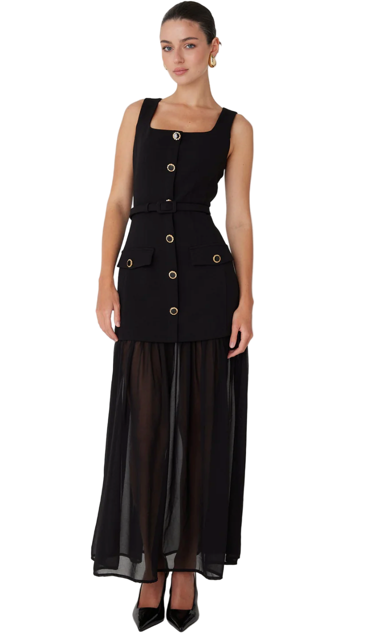 Woman wearing a black sleeveless dress with gold buttons on a white background